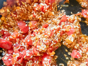 Arborio rice added to tomatoes, garlic and onion in a pan, Vegetarian Paella Recipe