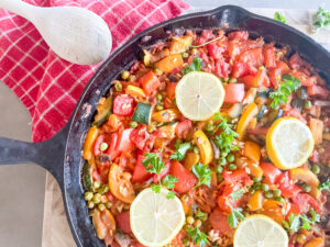 Vegetarian Paella Recipe, Paella with vegetables in a skillet, topped with lemons and parsley