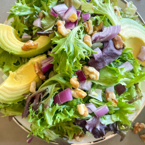 Mixed green salad with pepitas, onions, walnuts, and avocado